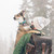 This is a man wearing a dark brown leather backpack in the snow and carrying a wounded dog.