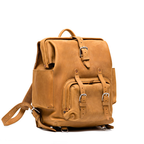 This is a tan brown leather backpack with a pocket on the front side.