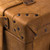 This is a leather trunk that will be a vintage antique one day in a museum. This is the corner. It is a tan brown steamer trunk that was old time luggage back in the day on trains and ships.